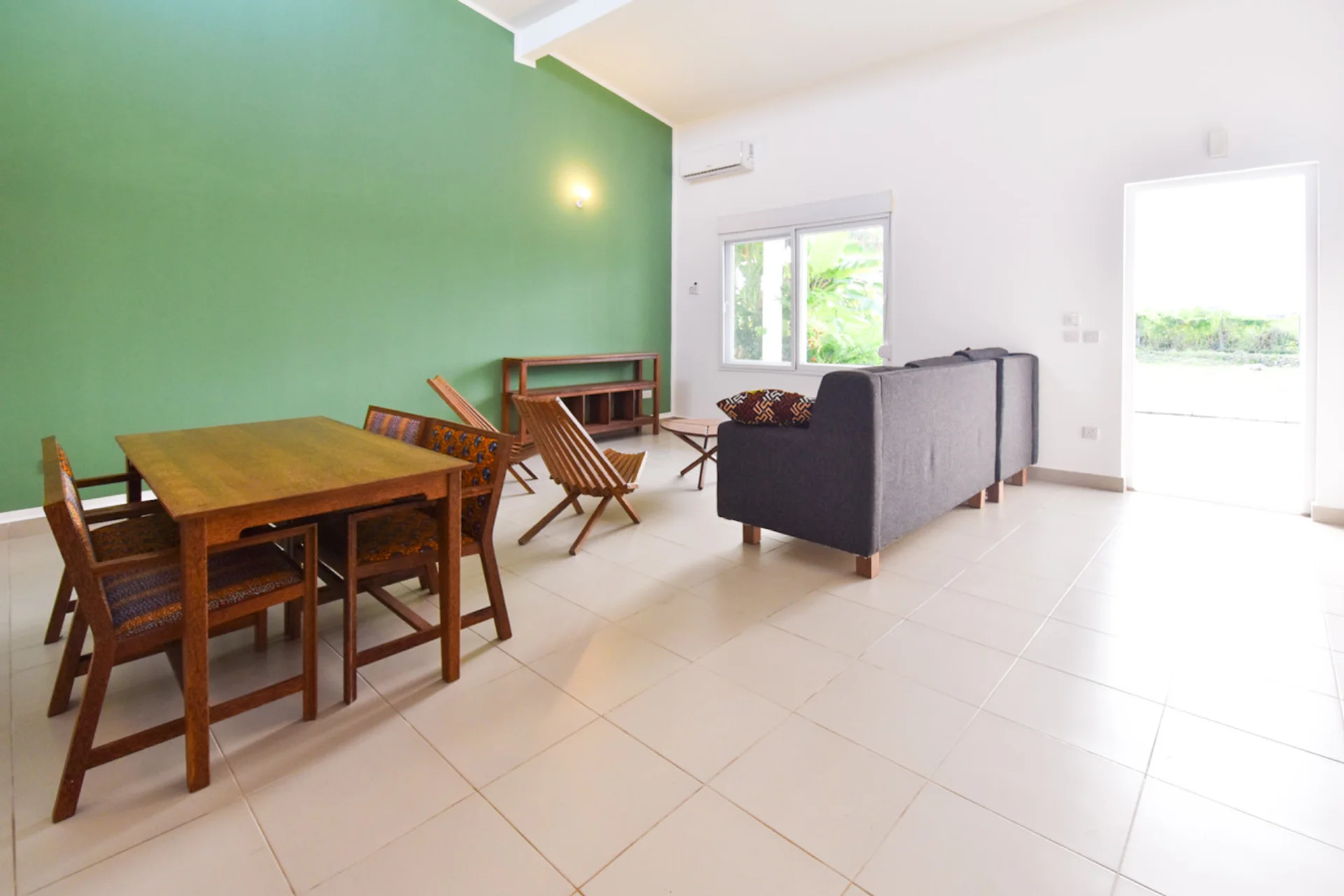 Open living and dining room with a green feature wall and timber dining table.
