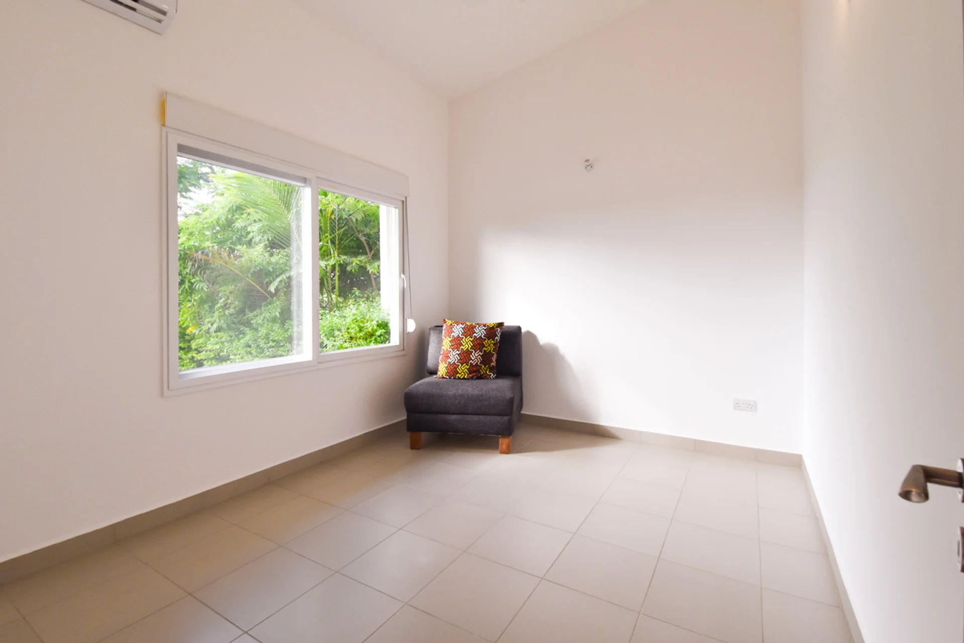 Bright spare room with a large window and a single upholstered chair.