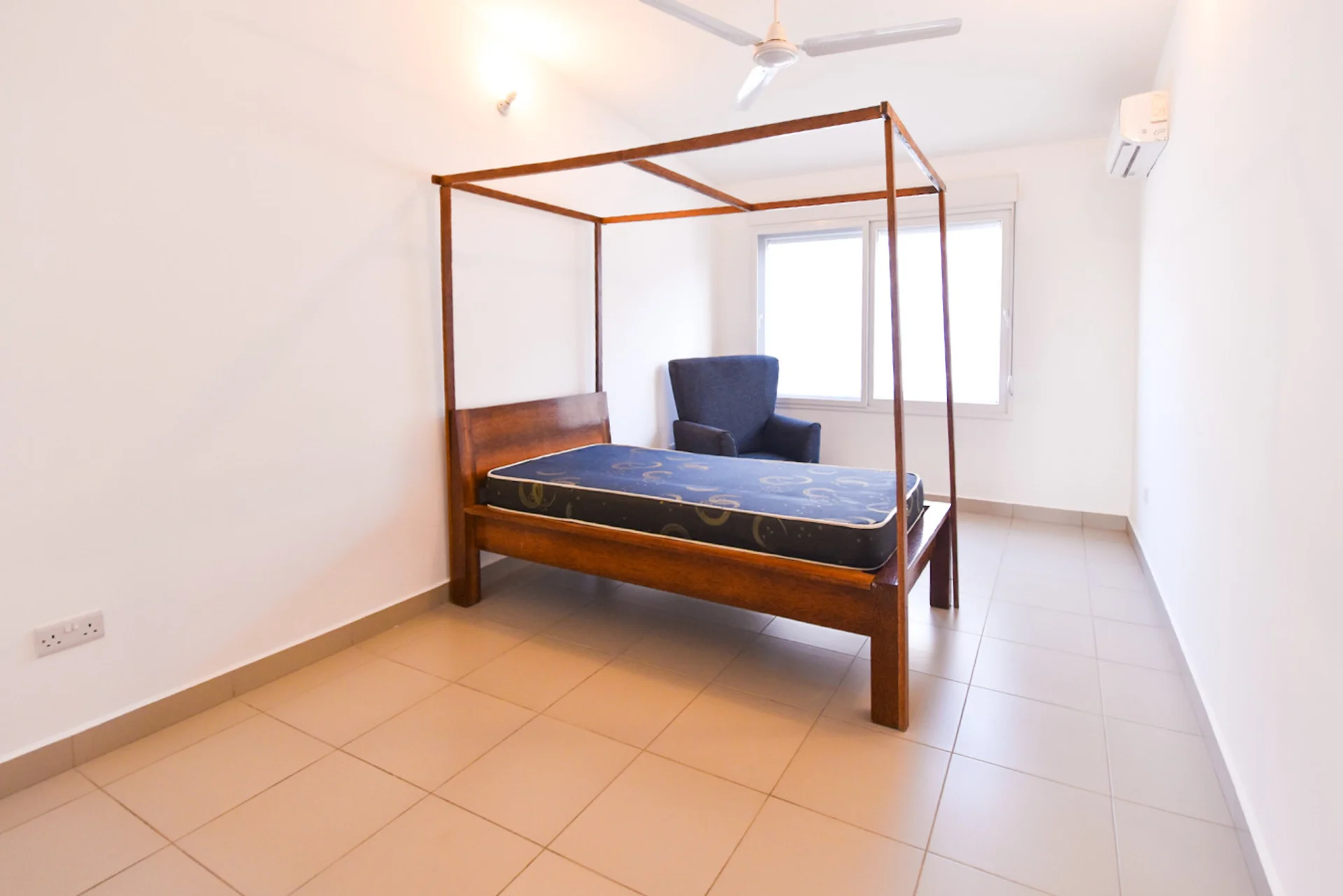 Bedroom with a timber four-poster bed, blue mattress, ceiling fan and a large window.
