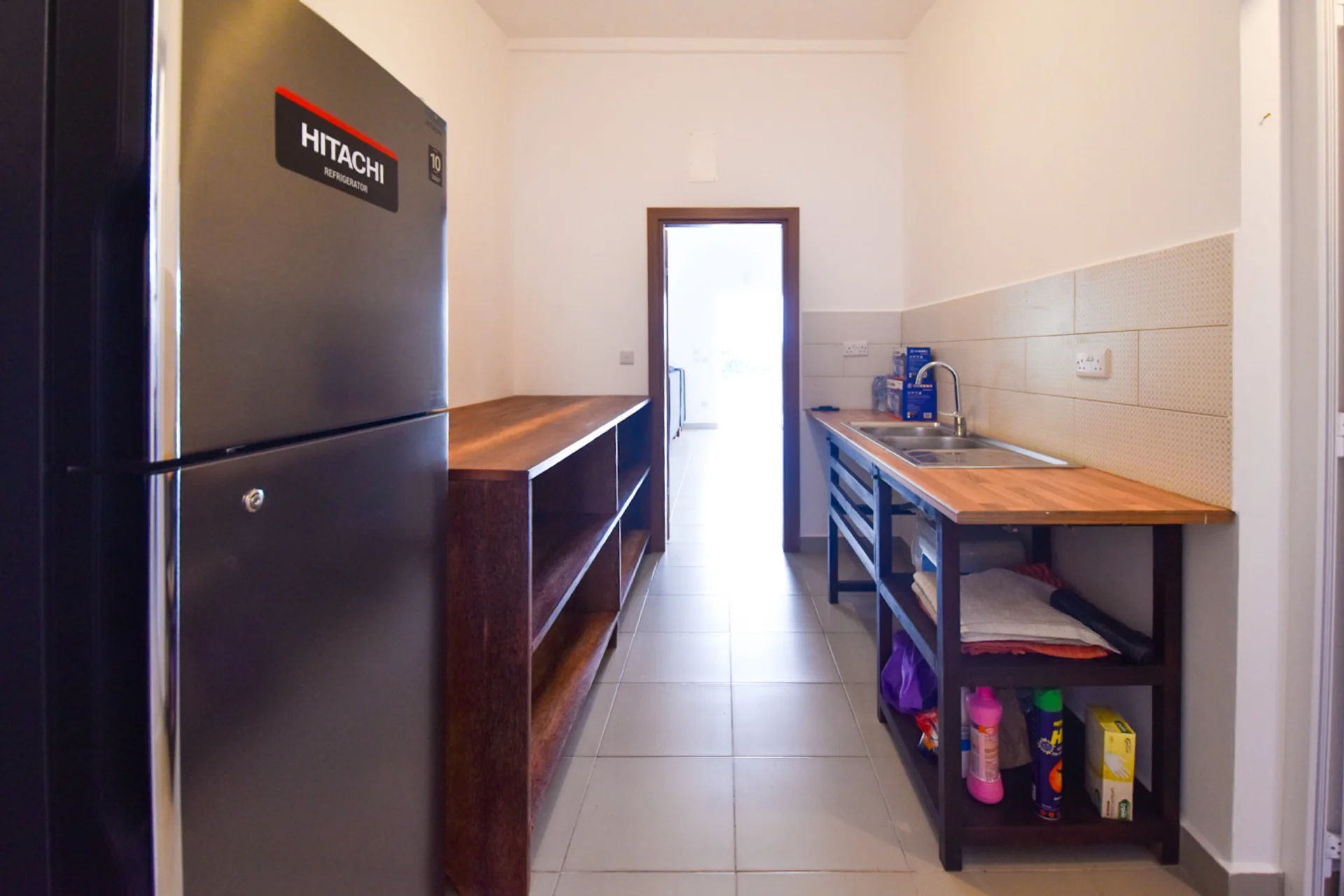 View along the kitchen from the refrigerator toward the open doorway.