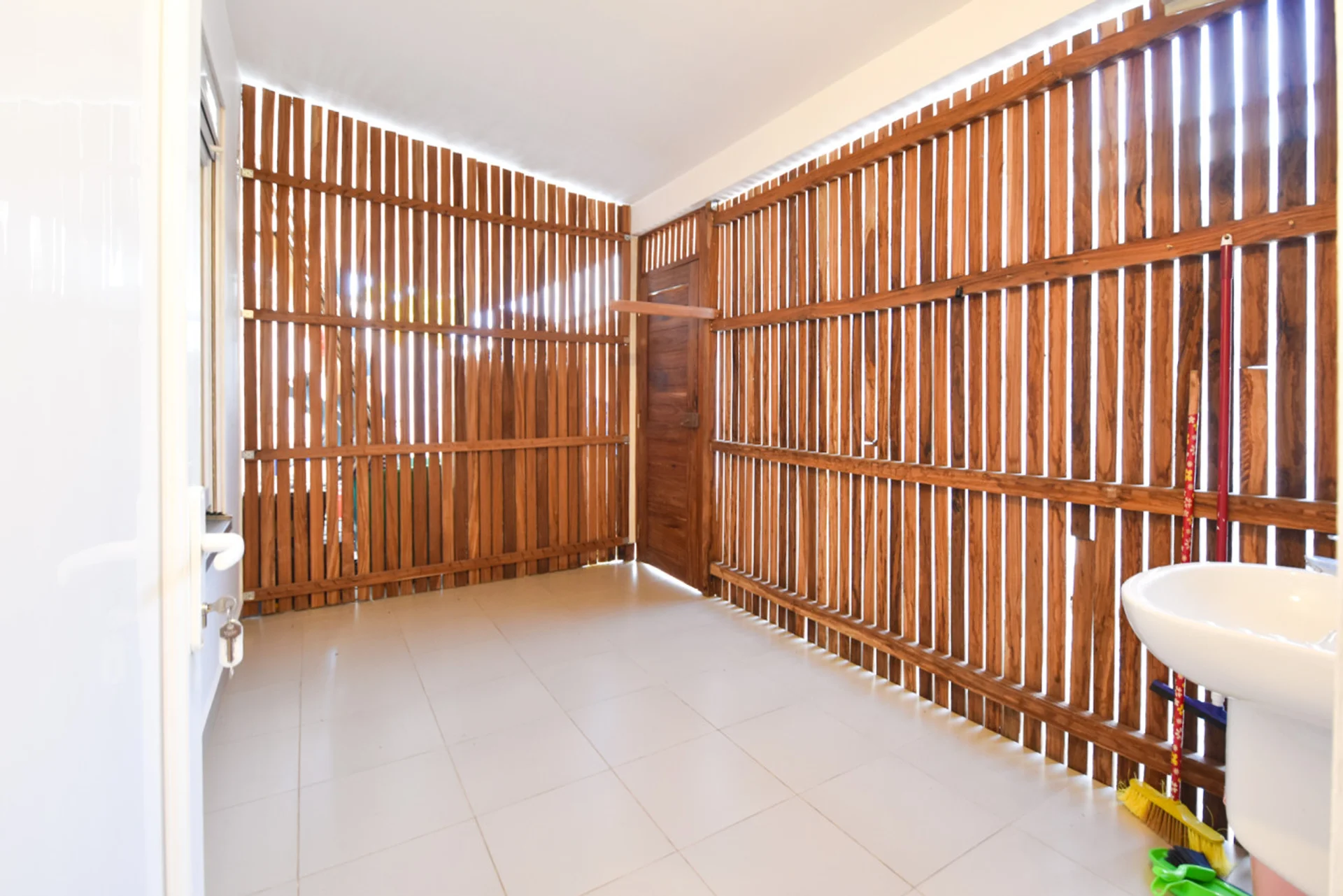Covered utility terrace with timber privacy screening and a small sink.