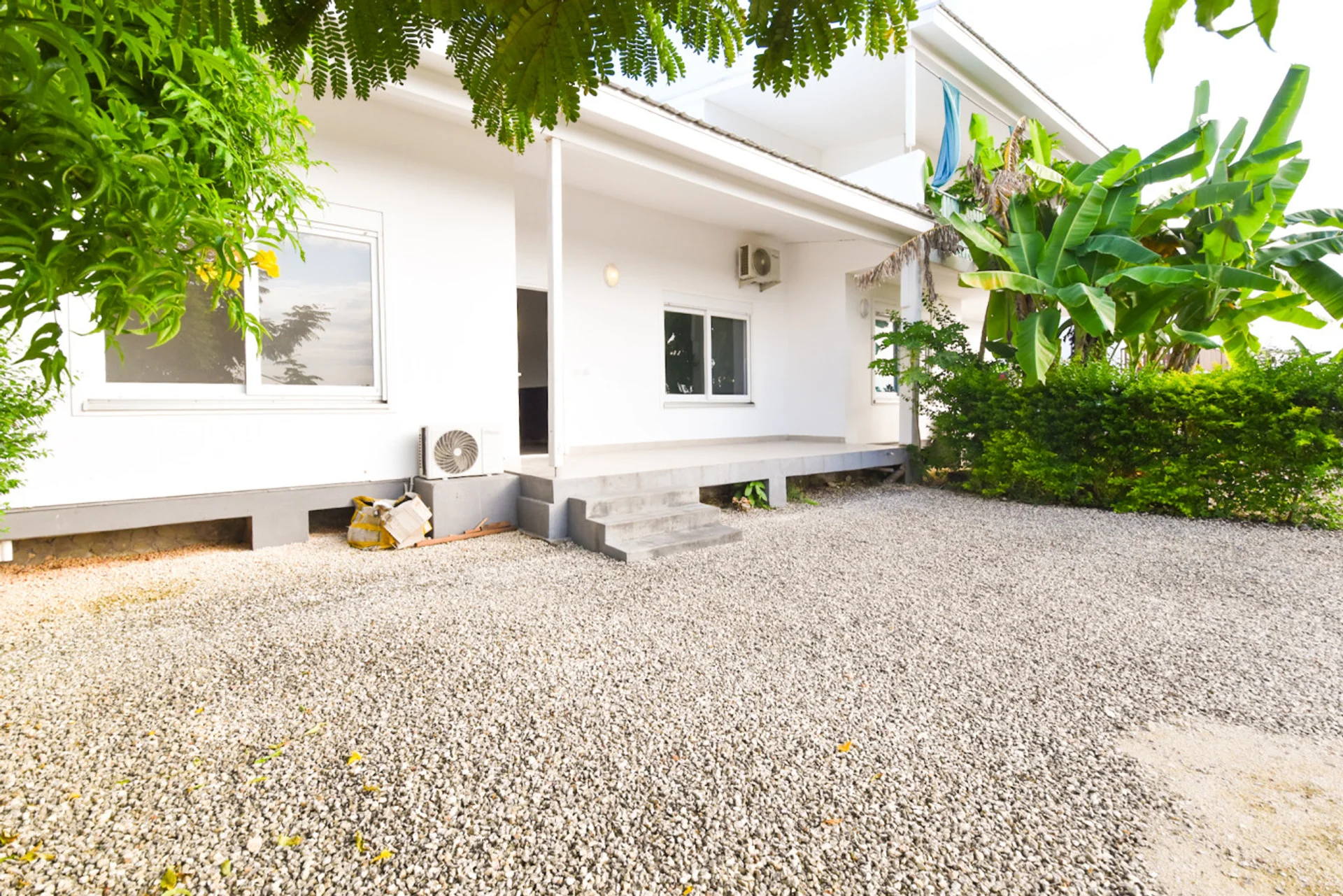 Garden courtyard and white townhouse facade framed by leafy tropical planting.